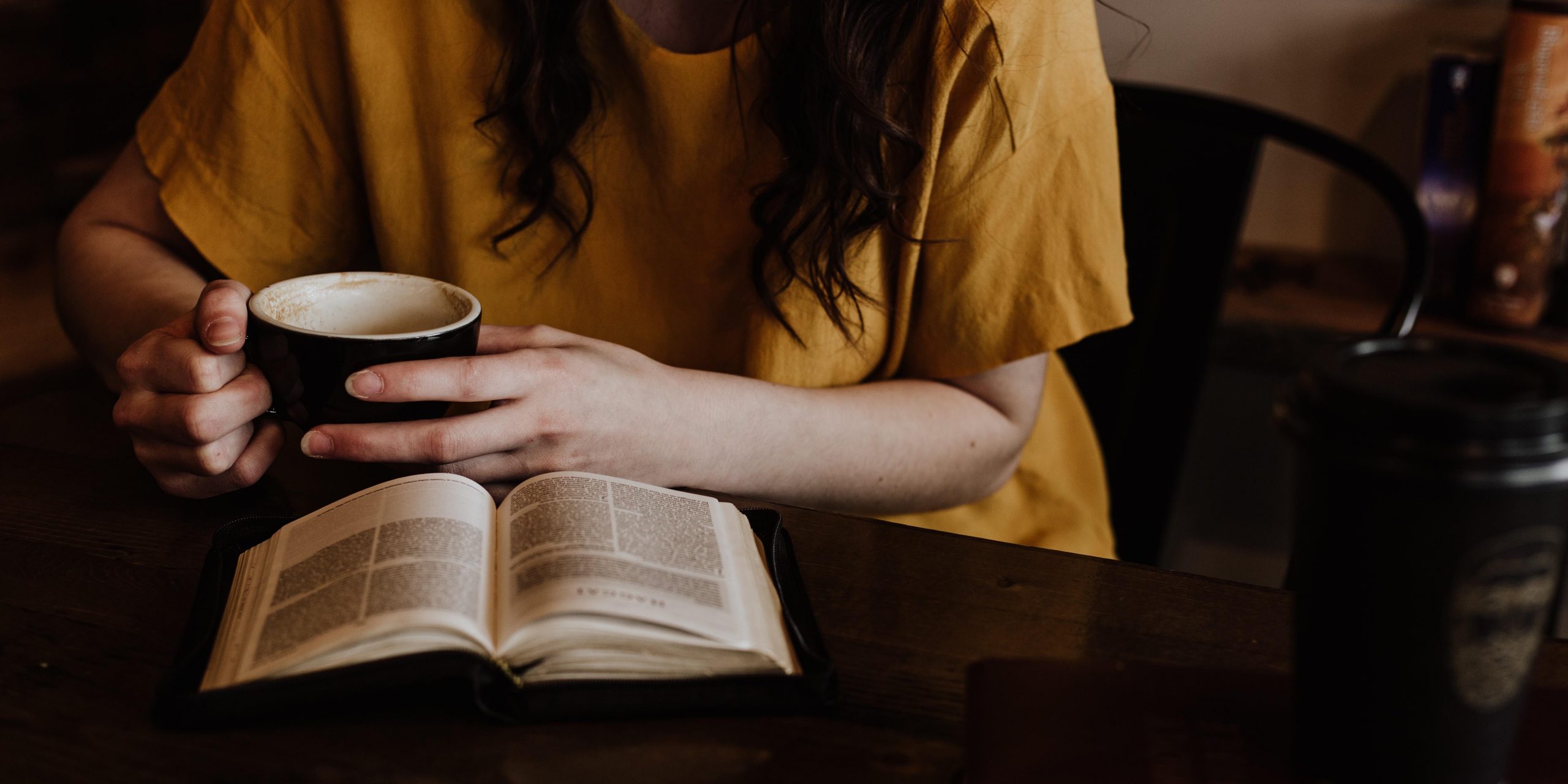 A person with a Bible and a cup of coffee