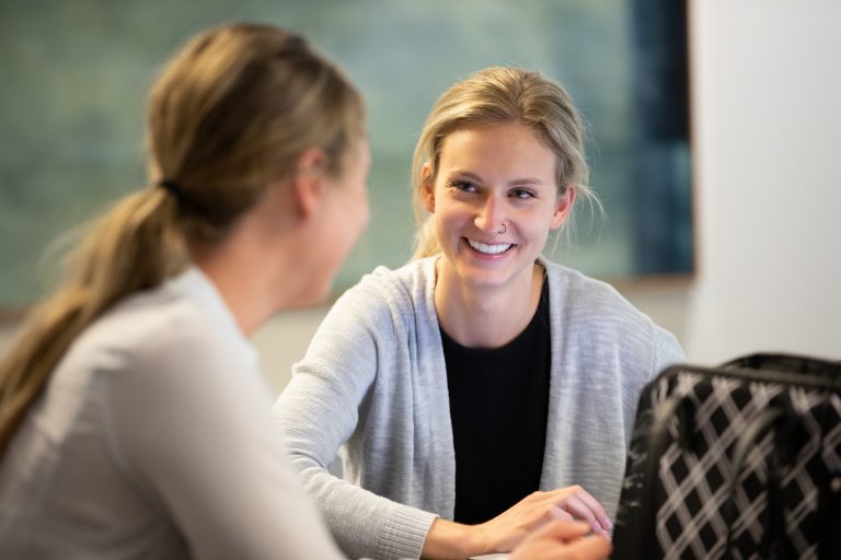 Two women facing each other studying at Bethel Seminary