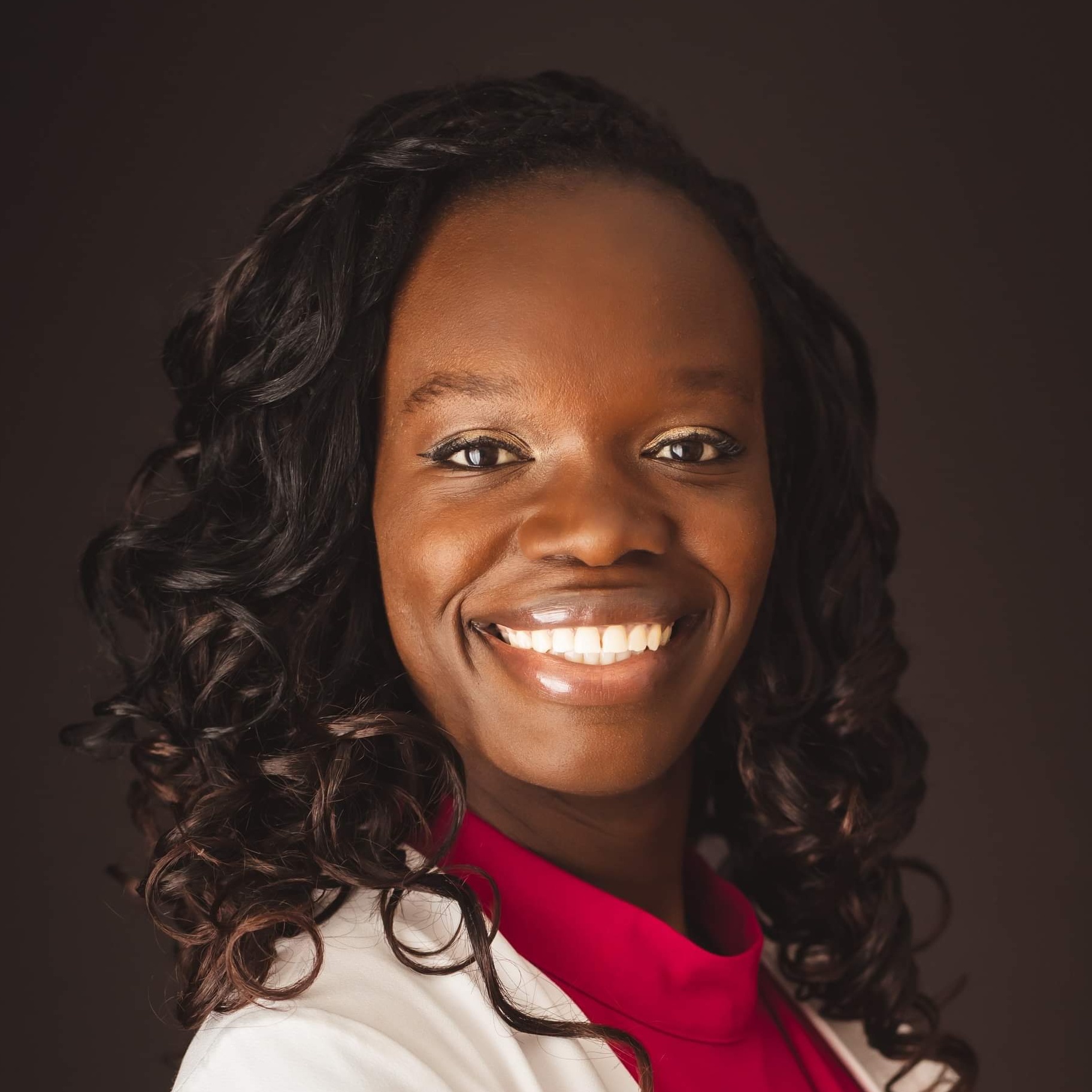 Smiling woman in a white blazer poses for a professional portrait.