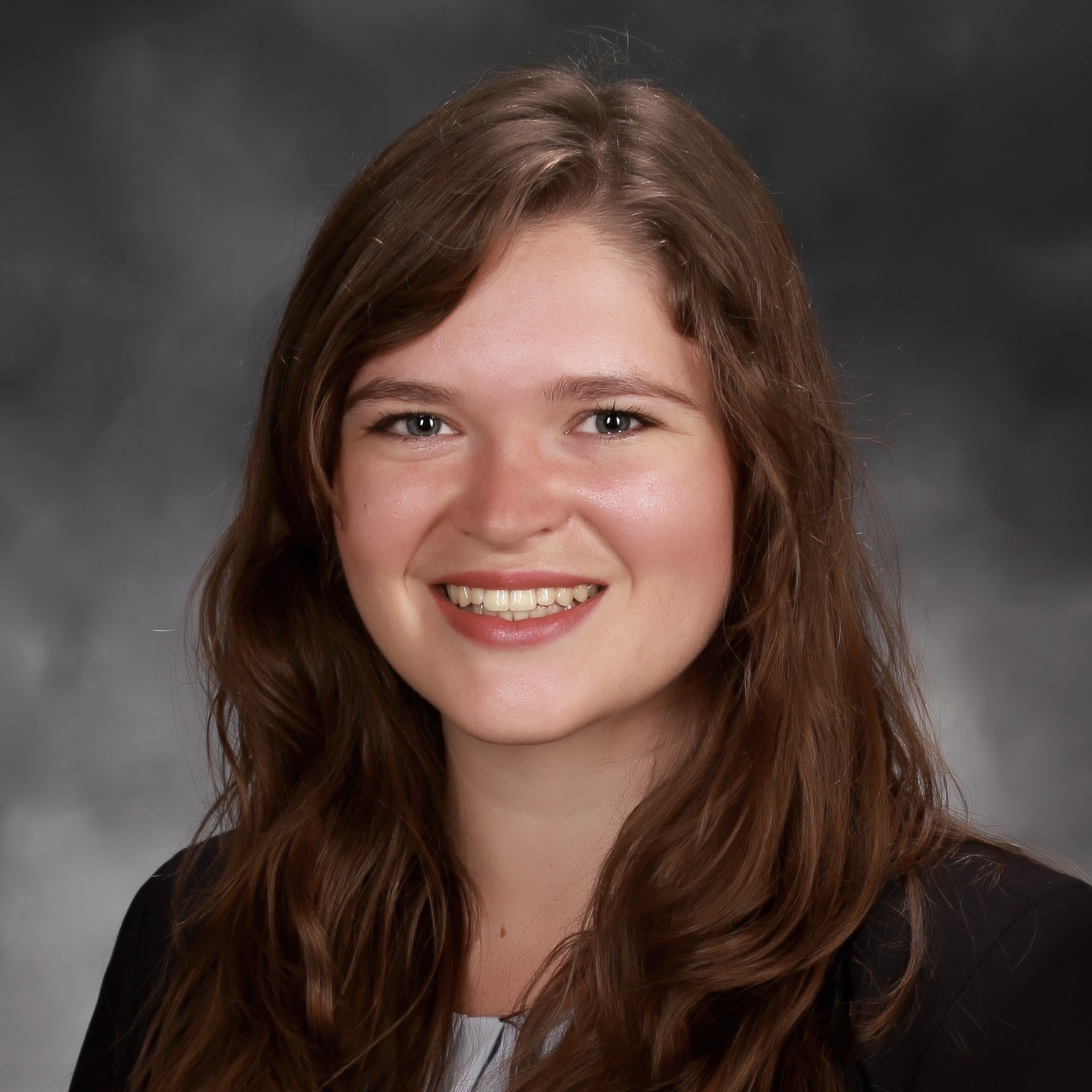 Smiling woman with long brown hair poses for a professional headshot.