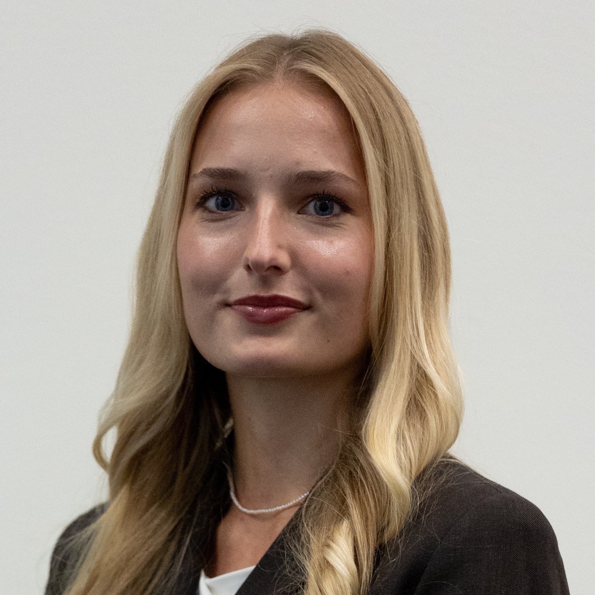 Eloise Nelson wears a dark blazer and pearl necklace for a professional headshot.